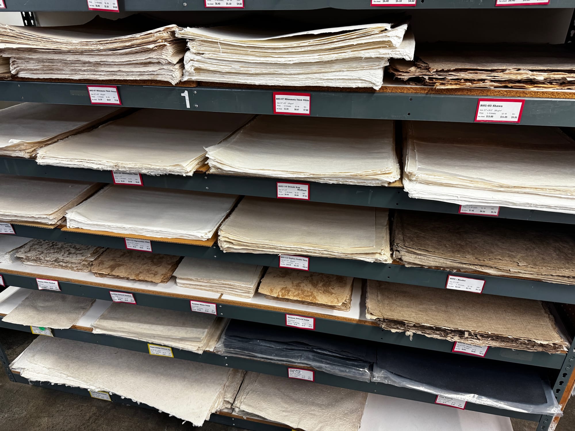 Several shelves with stacks of hand-made paper of various sizes from Hiromi Paper